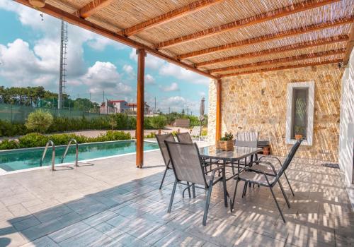un patio con mesa, sillas y piscina en Oliveto A Flumine - Experientia Villa, en Pastida