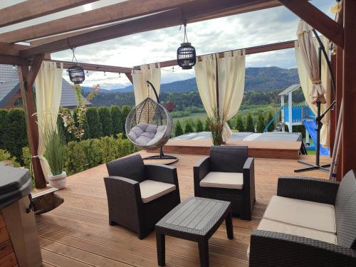 a patio with chairs and a swing on a deck at Apartament na wzgórzu in Muszyna