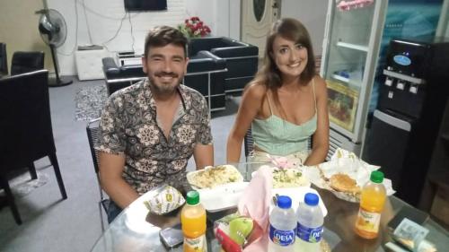 mężczyzna i kobieta siedzący przy stole z tortem w obiekcie Airport Kota Bharu Roomstay & Riverside Homestay w mieście Kota Bharu