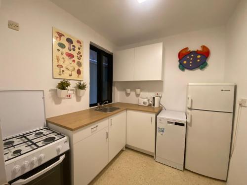 Tal-GħoqodにあるSt Julians Property with Terraceの白いキャビネットと白い冷蔵庫のあるキッチン