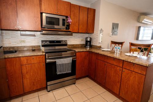 a kitchen with wooden cabinets and a stove and microwave at Private Jacuzzi Oasis with Mountain Views and FREE Parking in Ponce