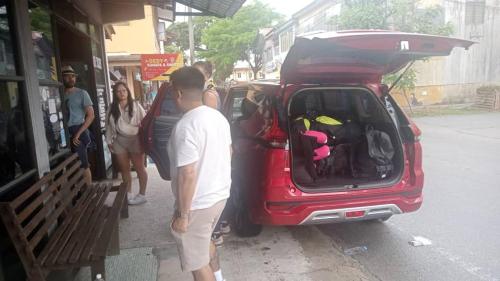 mężczyzna patrzący w otwarty bagażnik czerwonego samochodu w obiekcie Airport Kota Bharu Roomstay & Riverside Homestay w mieście Kota Bharu