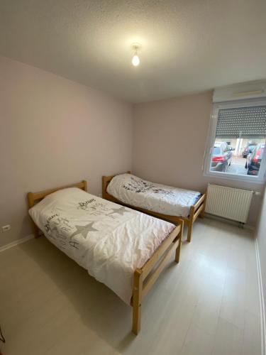 deux lits dans une petite pièce avec une fenêtre dans l'établissement Apparemment T4 avec 3 chambres et terrasses, à Besançon