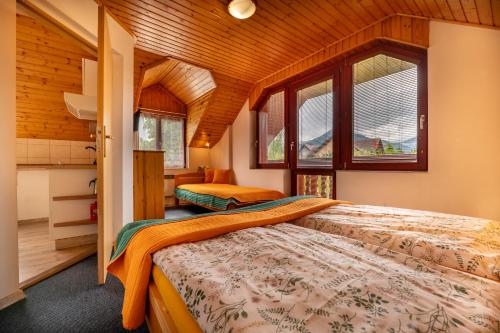 a bedroom with two beds and two windows at Penzion Fortuna in Liptovský Mikuláš