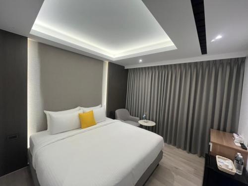 - une chambre avec un grand lit blanc et un oreiller jaune dans l'établissement 侎雅行旅 台中捷運站館 Mya INN, à Taichung