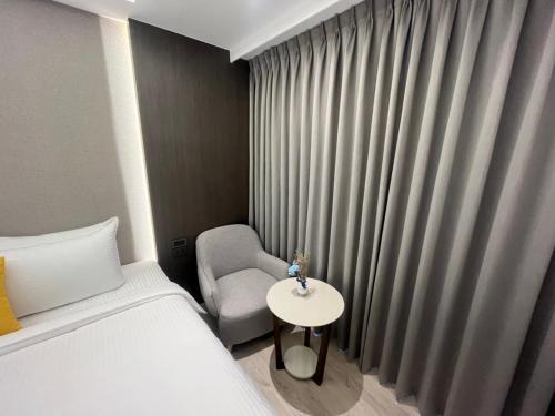 1 dormitorio con 1 cama, 1 silla y 1 mesa en 侎雅行旅 台中捷運站館 Mya INN, en Taichung