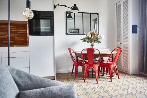 - une table à manger rouge avec des chaises rouges dans la cuisine dans l'établissement Charmante maison de bord de mer, à Houlgate