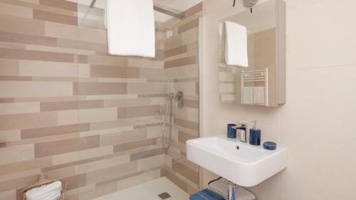 a white bathroom with a sink and a shower at Portopiccolo Apartments in Sistiana