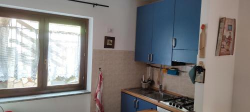a kitchen with blue cabinets and a window at Villetta Le Rocche - Rocca di Cambio in Rocca di Cambio