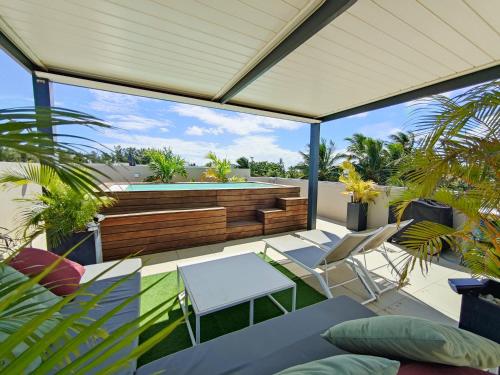 an outdoor patio with chairs and a swimming pool at Villa Eden-2 bedrooms with Private Rooftop Terrace & Pool & access to private beachclub, Ki Residences, Pereybère, Grand Baie in Grand Baie