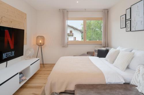 1 dormitorio blanco con 1 cama grande y TV en FENJOY: Großes Ferienapartment im Neubau / Balkon / BBQ, en Bernau am Chiemsee