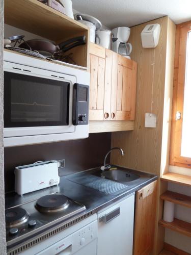 une cuisine avec une cuisinière et un micro-ondes dans l'établissement Vamorel, appartement pour 4 au pied des pistes., à Valmorel