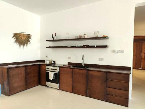 a kitchen with wooden cabinets and a sink and a stove at Luxury White Villa in Nungwi
