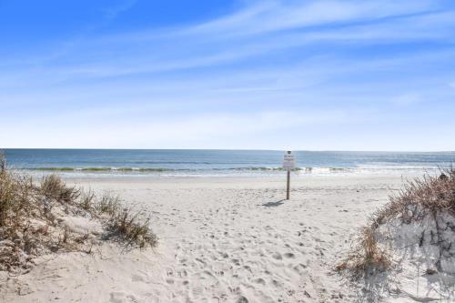a sign in the sand on a beach at Sea Oats 102C- Beach view Pool 25 steps to beach in Gulf Shores