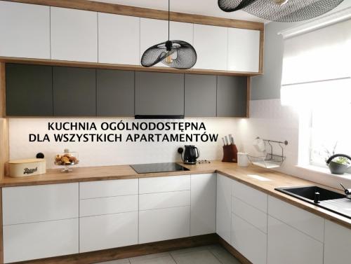 - une cuisine avec des placards blancs et des comptoirs en bois dans l'établissement Apartamenty DELUXE-Willa DAHARA-Grupa PlażoweLove, à Krynica Morska