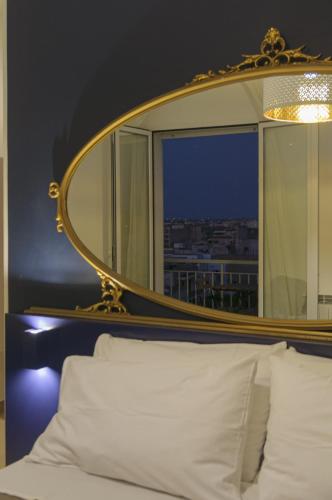 a mirror above a bed with white pillows in a room at B&B Sbarco dei 1000 Marsala in Marsala