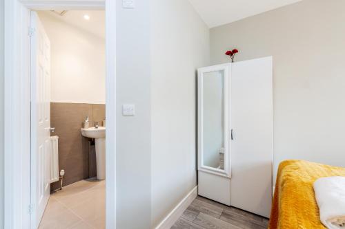 1 dormitorio con armario blanco y lavamanos en Dartford, Kent - Modern 2Bd 2Bath En-Suite Bungalow M25 Bluewater en Dartford