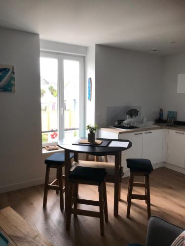 une cuisine avec une table et des chaises dans une pièce dans l'établissement Location saisonnière type 2 4 personnes, à Fouesnant