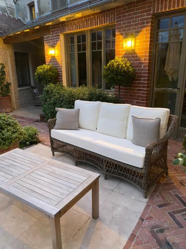 a wicker couch with pillows sitting on a patio at Les Hortensias in Canly