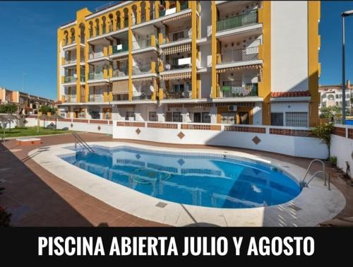 a hotel with a swimming pool in front of a building at Apartamento en el Portil in El Portil