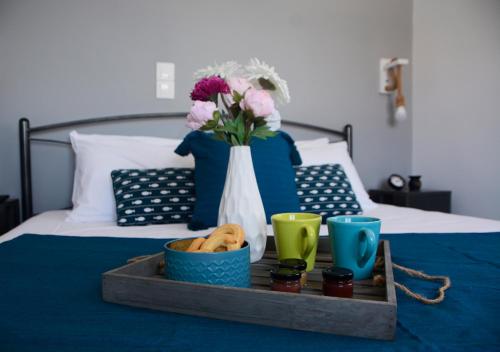 バトシにあるBatsi Bayの花瓶を用いたベッドの上に食料品を並べたトレイ
