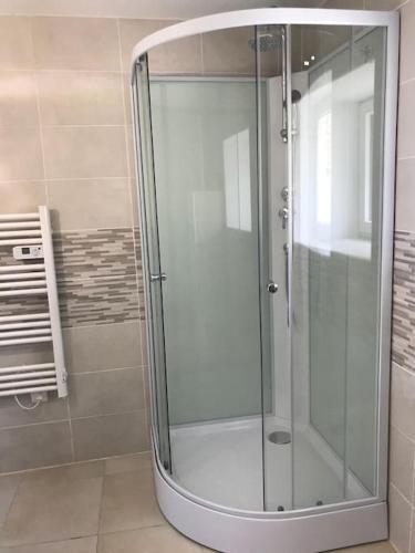 une douche avec une porte vitrée dans une salle de bain dans l'établissement Gîte du Marquès, à Sainte-Brigitte