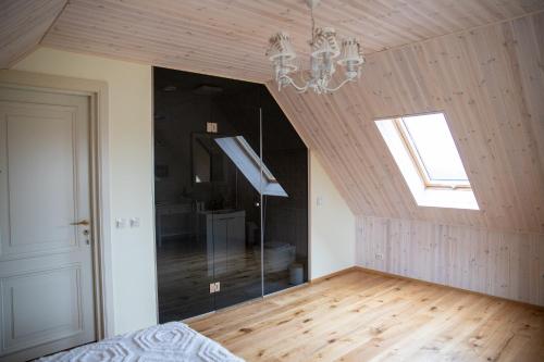 an attic room with a chandelier and wooden floors at Muhu Kulla Saadu puhkemaja mere ääres in Raugi