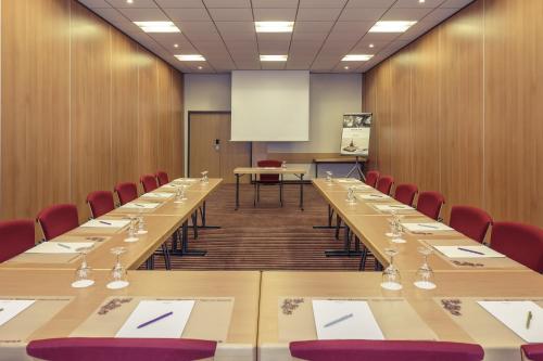 a large conference room with long tables and red chairs at Mercure Hotel Frankfurt Eschborn Ost in Eschborn