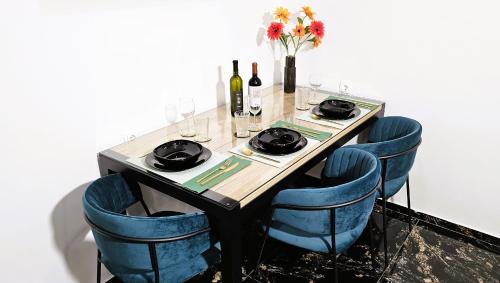 a table with blue chairs and wine bottles and flowers at Studio Kamarin in Buzdohanj