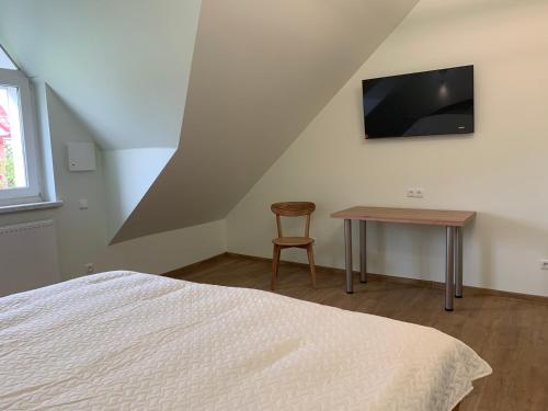 a bedroom with a bed and a table and a television at Green House in Ramučiai