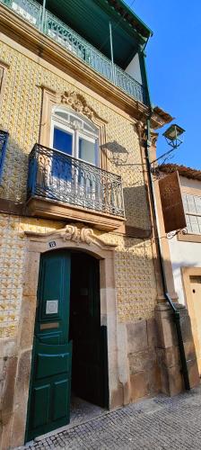 a building with a green door and a balcony at Casa Da Avo - Turismo De Habitacao in Torre de Moncorvo