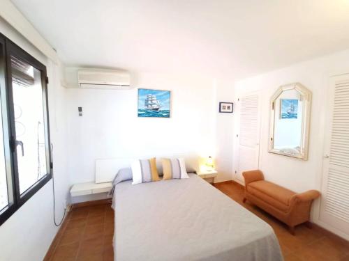 a white bedroom with a bed and a chair at Sea Views Benidorm Beach in Benidorm