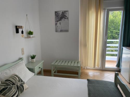 Schlafzimmer mit einem Bett, einem Tisch und einem Fenster in der Unterkunft Ξενοδοχειο Julietta in Patitiri