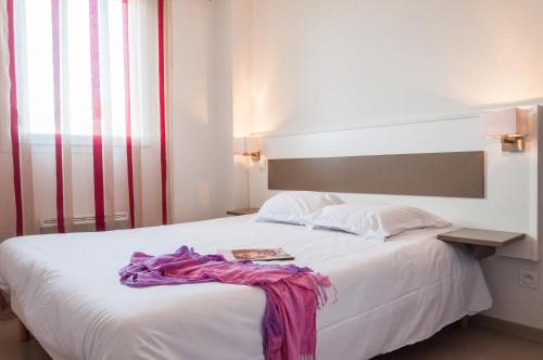 ein Schlafzimmer mit einem weißen Bett mit einem Buch darauf in der Unterkunft Vacancéole - Les Demeures Torrellanes - Saint-Cyprien in Saint-Cyprien