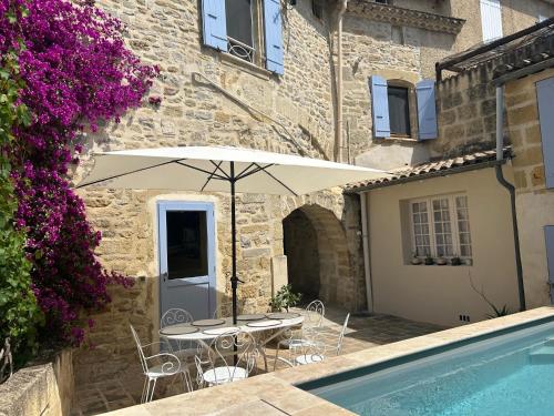 un patio avec une table, des chaises et un parasol dans l'établissement Le prieuré, à Gallargues-le-Montueux