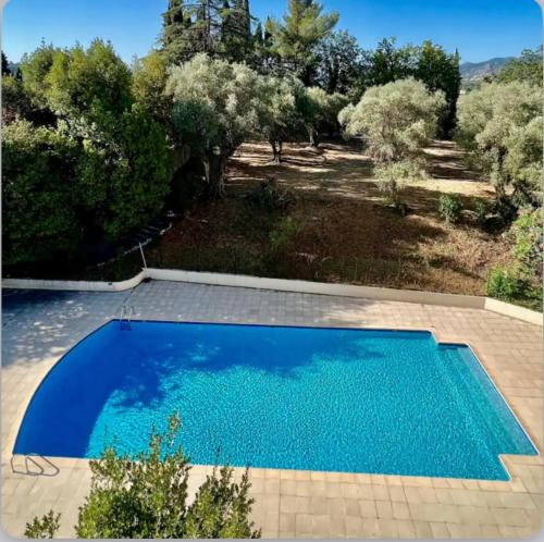 une piscine bleue dans une cour arborée dans l'établissement Très bel appartement, à Cannes