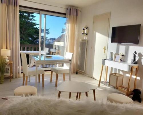 un salon avec une table, des chaises et une télévision dans l'établissement Studio front de mer, à Merville-Franceville-Plage