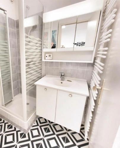 une salle de bain blanche avec un lavabo et une douche dans l'établissement Studio front de mer, à Merville-Franceville-Plage