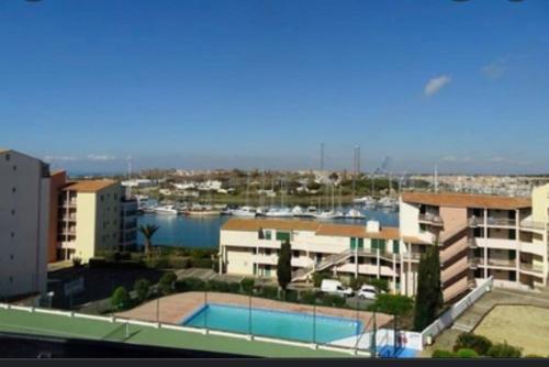 une vue d'une marina avec des bâtiments et une piscine dans l'établissement Charmant studio île des pêcheurs piscine tennis, au Cap d'Agde