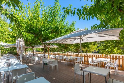 a deck with tables and chairs and an umbrella at Hotel Rosaleda del Mijares in Montanejos