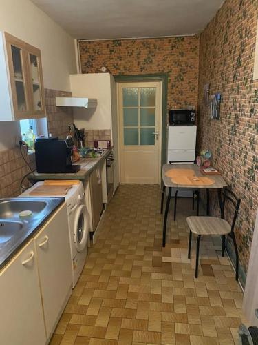 Il comprend une cuisine équipée d'un évier, d'une table et d'une cuisinière. dans l'établissement Appartement centre St-Mihiel, à Saint-Mihiel