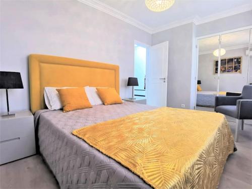 a bedroom with a large bed with a yellow blanket on it at Casa Tulipa Ferias - Vilamoura in Quarteira