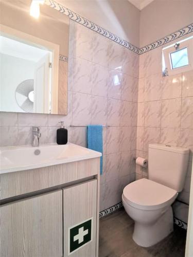 a bathroom with a white toilet and a sink at Casa Tulipa Ferias - Vilamoura in Quarteira
