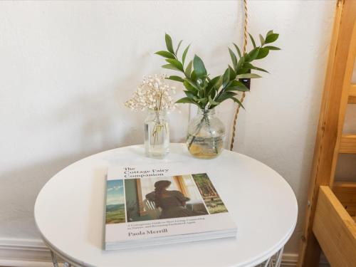a table with a book and a vase with flowers on it at Convenient & Inviting - Fully-Equipped 2BD Condo in Gainesville