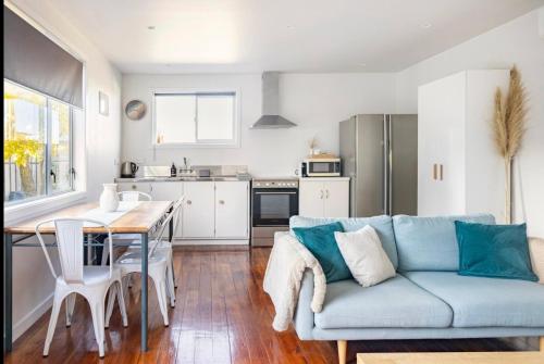 sala de estar con sofá azul y cocina en Sunny Modern Cottage - Close to Airport, en Napier