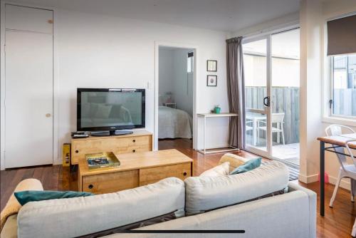 sala de estar con sofá y TV de pantalla plana en Sunny Modern Cottage - Close to Airport, en Napier