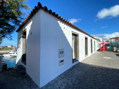 a white building with a door next to the water at T0 com mezanino à beira-mar in Madalena