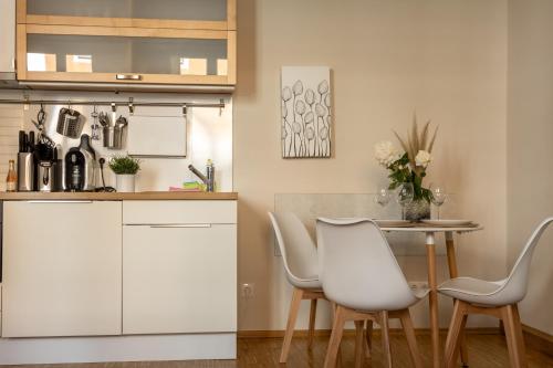 a kitchen with white cabinets and a table and chairs at Ein gemütliches Studio mit Netflix im Zentrum Bahnhofsnähe in Coburg