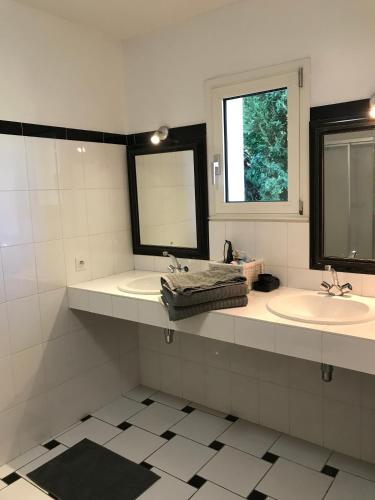 une salle de bain avec deux lavabos et deux miroirs dans l'établissement Thebertisa, à Valréas