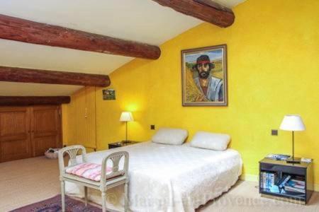 - une chambre jaune avec un lit et une chaise dans l'établissement Thebertisa, à Valréas